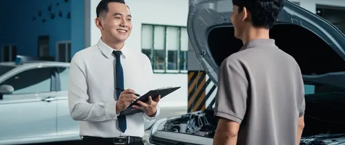 Cố vấn dịch vụ trao đổi với khách hàng bên xe Toyota mở nắp ca-pô
